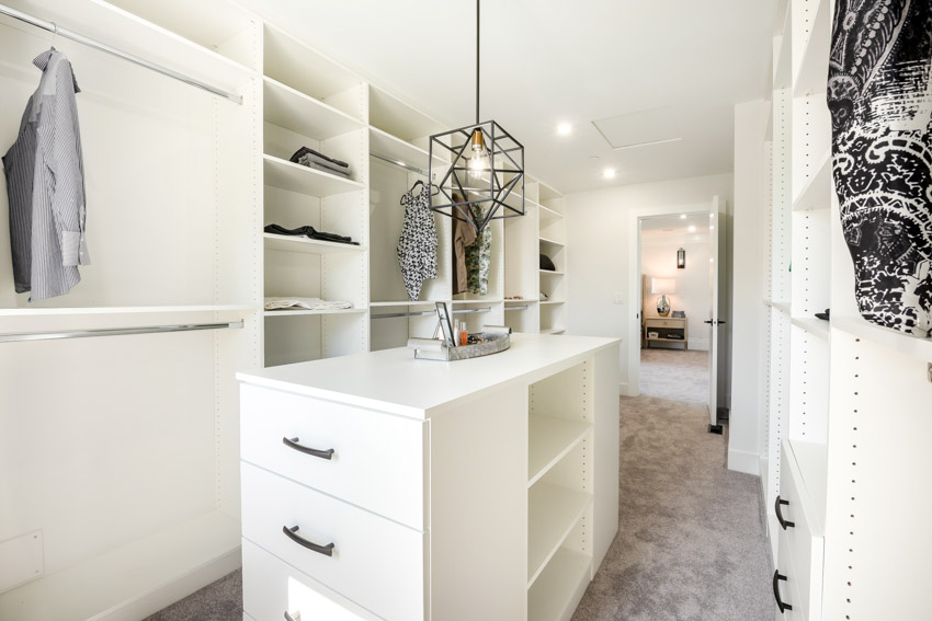 White walk-in closet with drawers, center island, and hanging light
