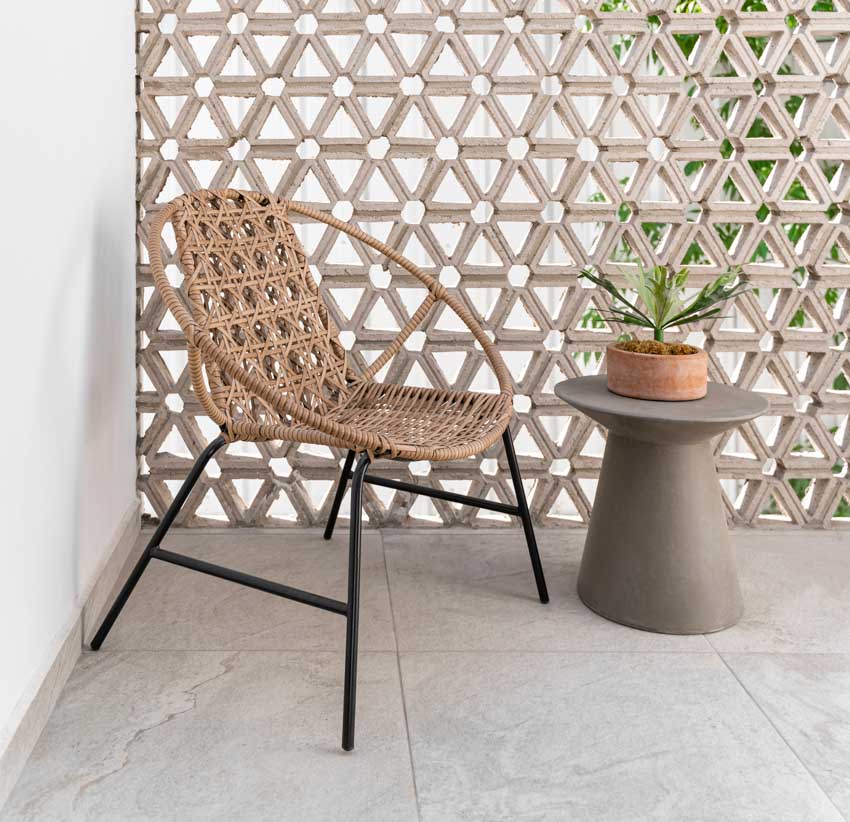 Wicker chair with metal legs with small table on concrete flooring