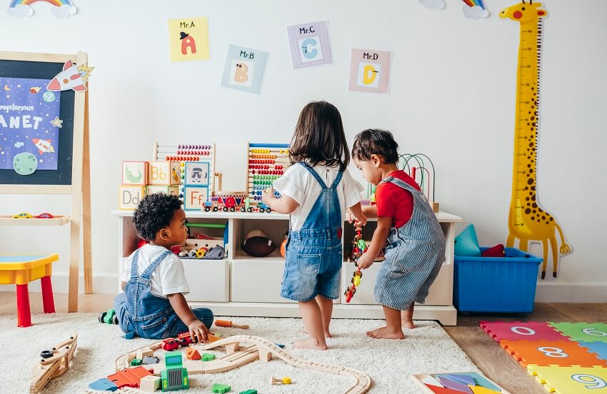 Children enjoying in the playroom with wall decors, white shelves and giraffe wall decor