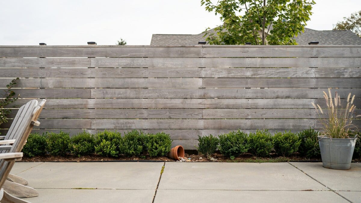 Horizontal plank wood fence bordering a backyard patio