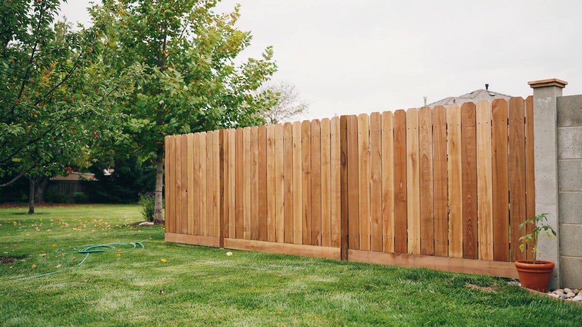 Wood fence panel with a decorative scalloped top in a backyard