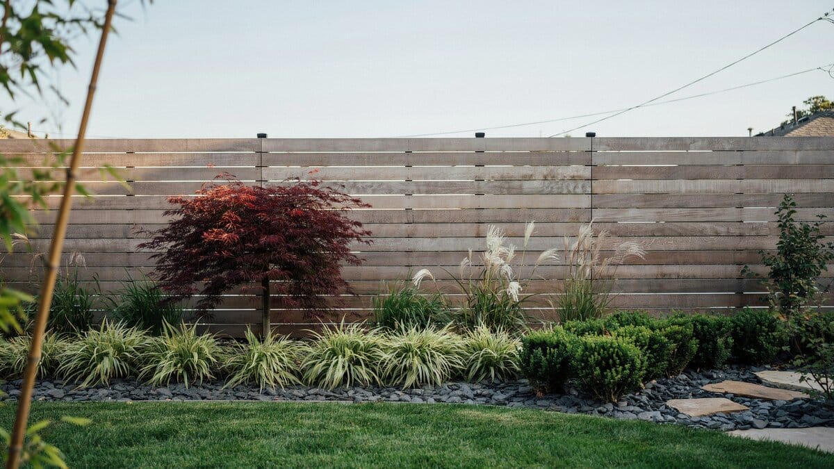 Asian landscaping with a custom horizontal plank privacy fence and ornamental plants