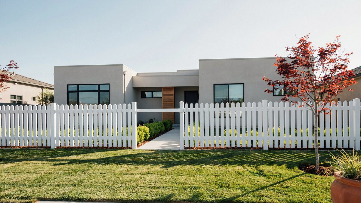 Clean modern white picket fence along a contemporary front yard
