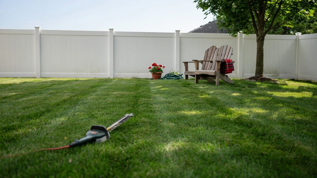 White vinyl fence enclosing a green backyard
