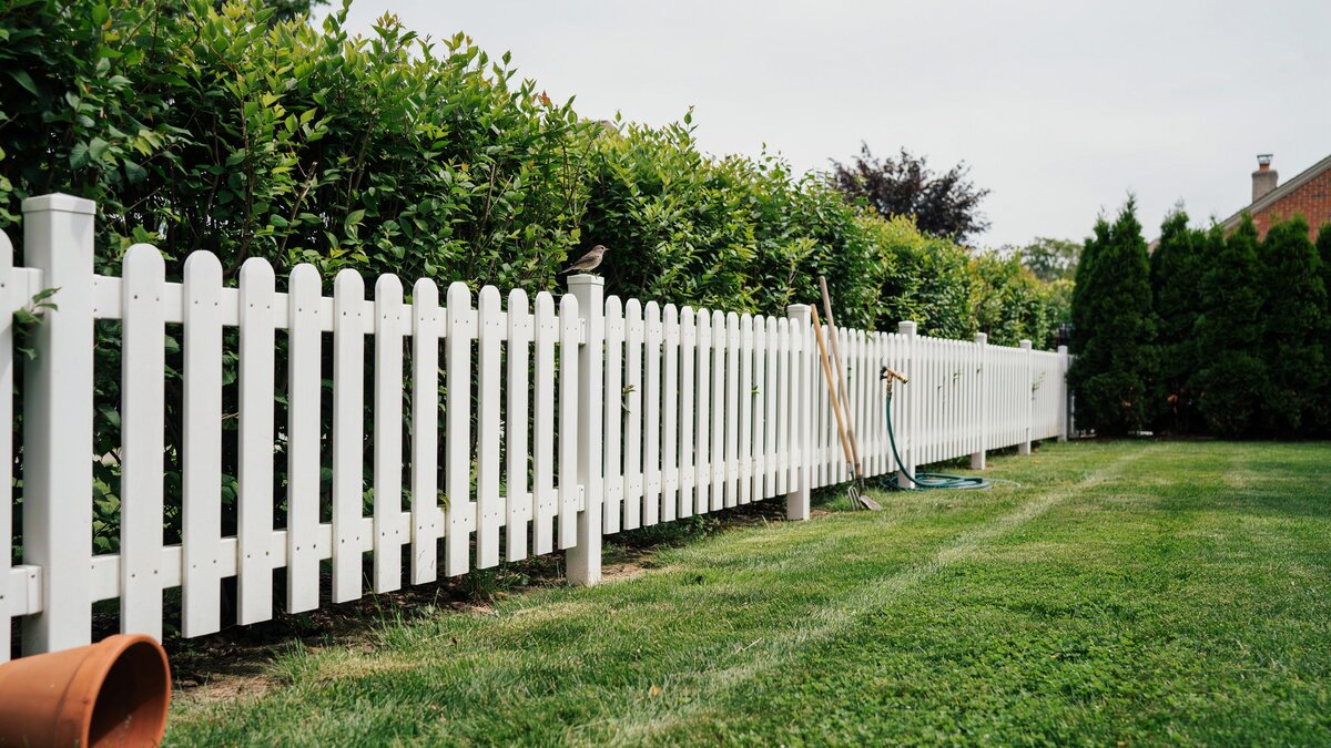 White resin fence bordering a green garden