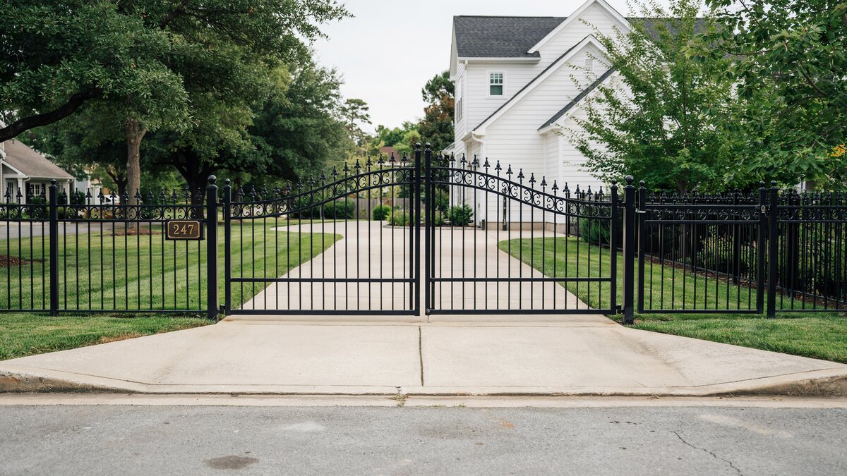 Black wrought iron gate at a residential driveway entrance