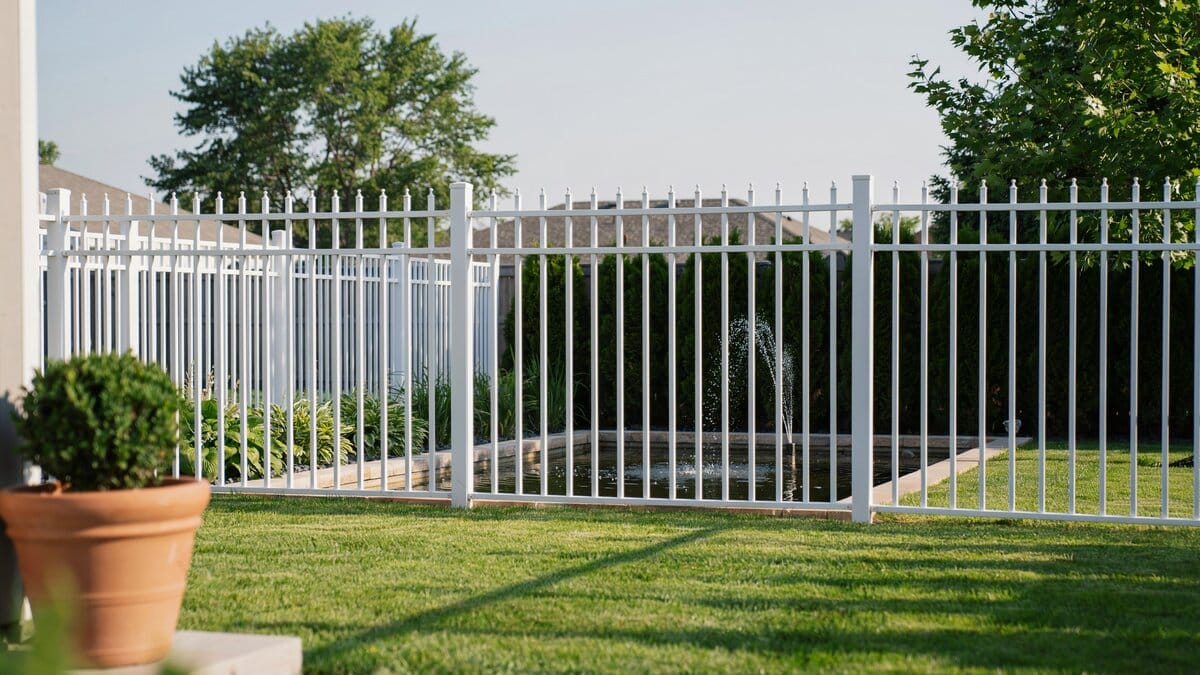White aluminum fence surrounding a backyard water feature