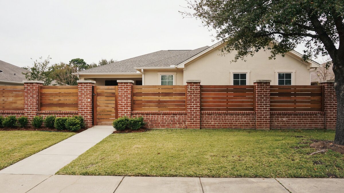 Exterior fence with brick columns and wood infill panels in front of a house