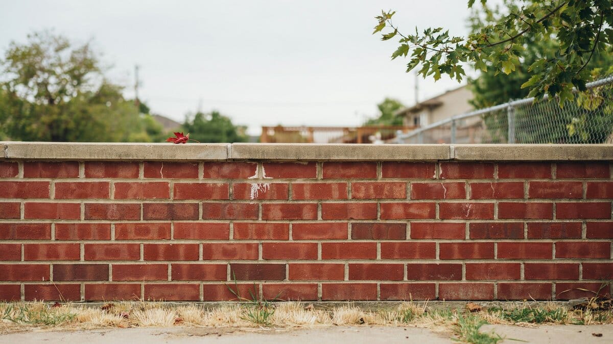 Solid red brick fence wall along a property line