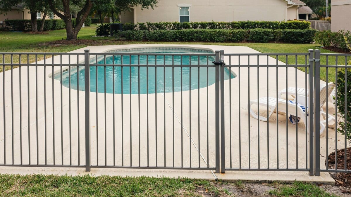 Gray metal safety fence around a backyard swimming pool