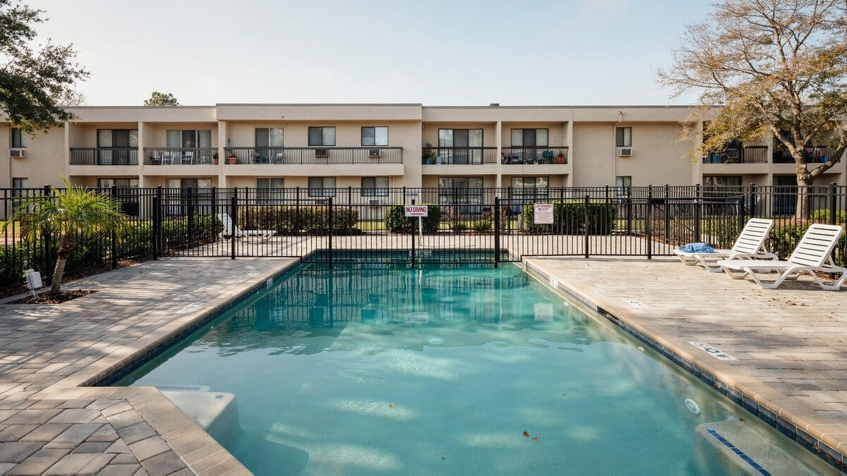 Black metal fence around an apartment swimming pool with paver decking