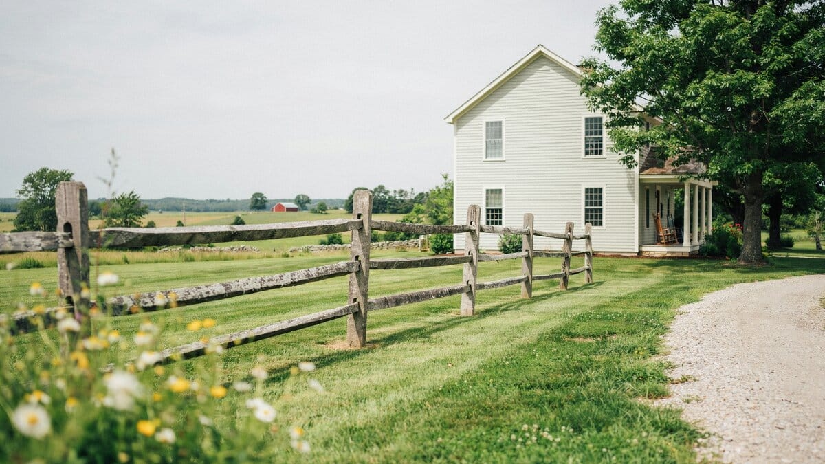 Wood post and rail fence in front of a country home