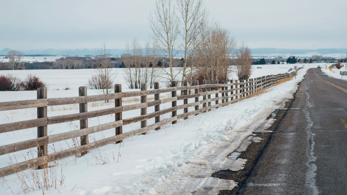 Wood slat snow fence along a snowy roadside