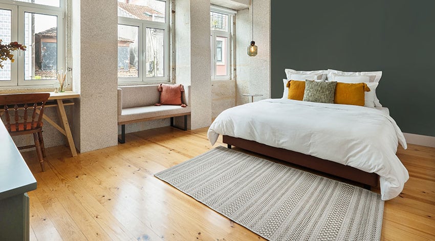 Apartment bedroom with hardwood flooring casement windows with rug