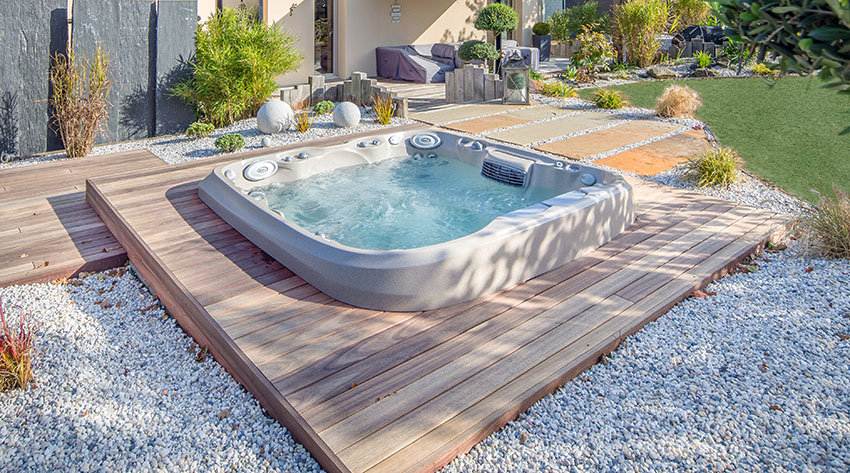 In-ground spa with wood deck and riverbed stones