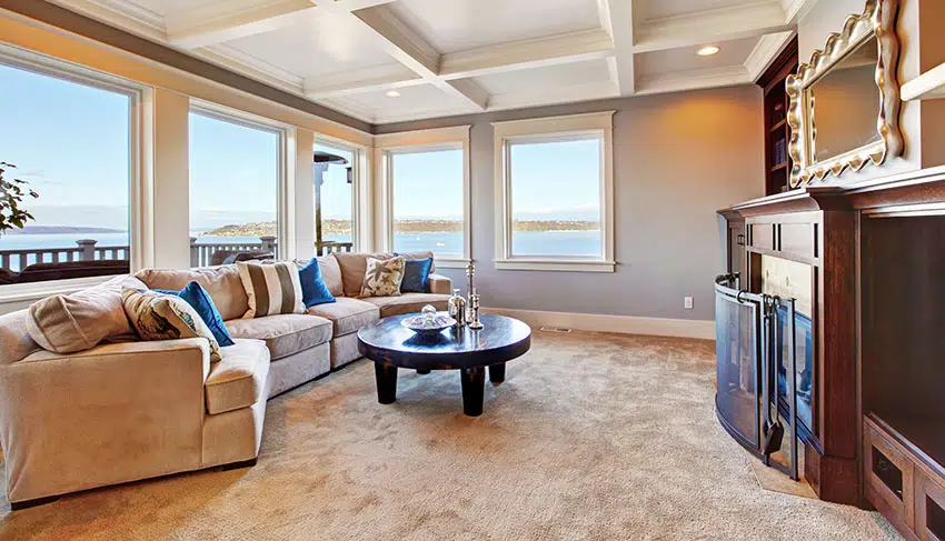 Room with picture windows, couch, round coffee table and carpeted floors