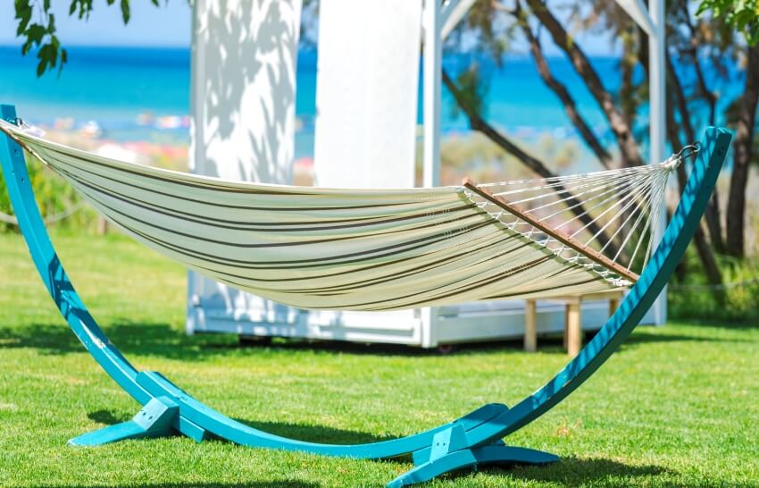 A hammock on a blue wooden stand with a seascape background