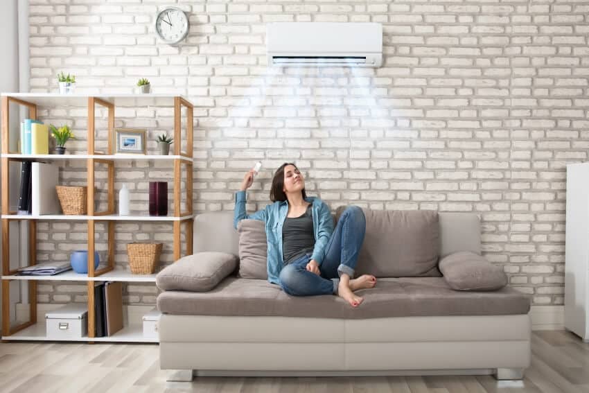 A woman relaxing on a sofa under the air conditioner on a brick wall