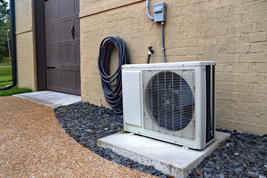 Air conditioner mini split system next to home with painted brick wall