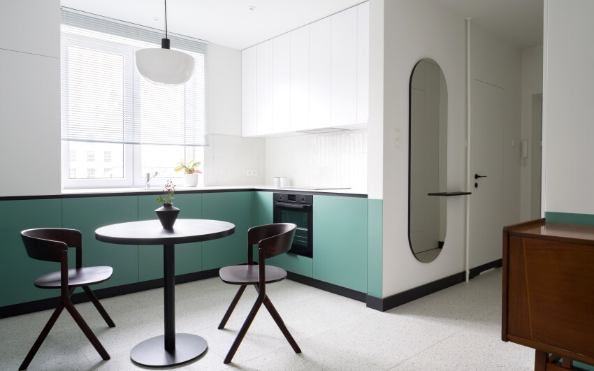 Apartment with modern white and mint kitchen with black dining table chairs and terrazzo floor