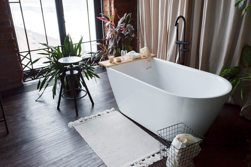 Bathroom with acrylic tub, indoor plant, faucet, and indoor plant