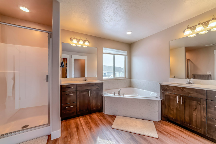 Bathroom with acrylic tub, shower area, wood floor, and accent lights