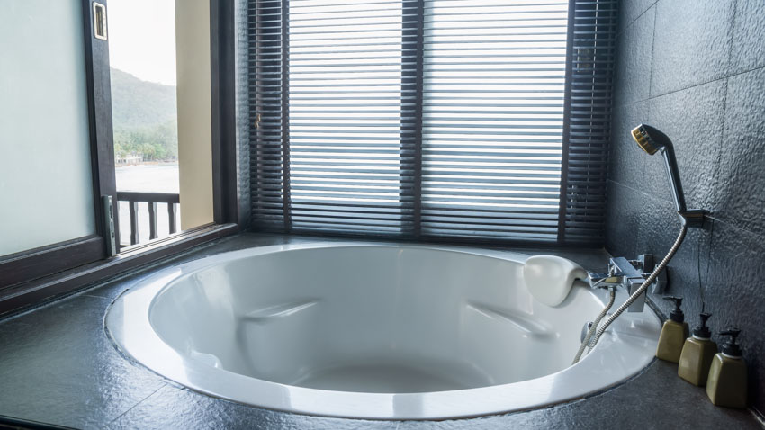 Bathroom with acrylic tub, windows, and showerhead
