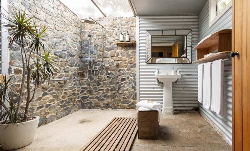 Beautiful bathroom with stone wall, shower area, sink, and potted plant