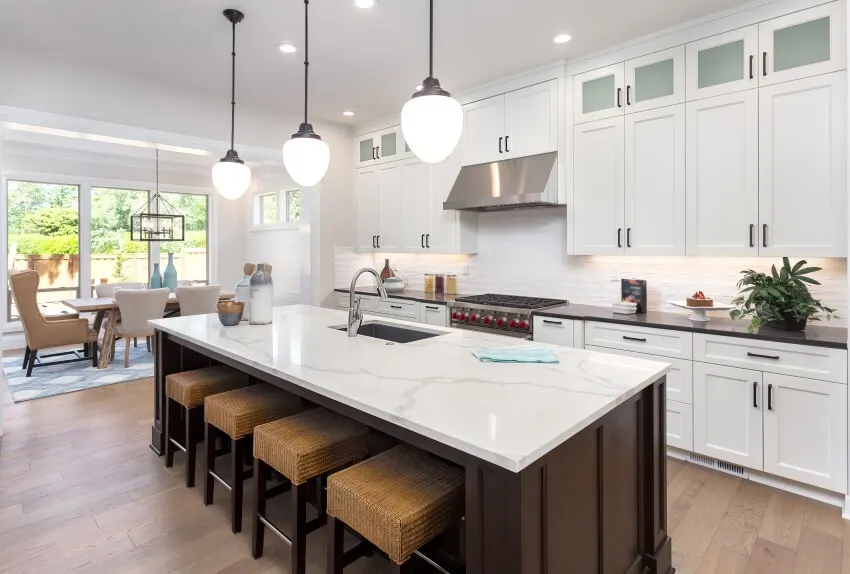 Beautiful kitchen with mixed countertops, island, subway tile backsplash, and view of dining room