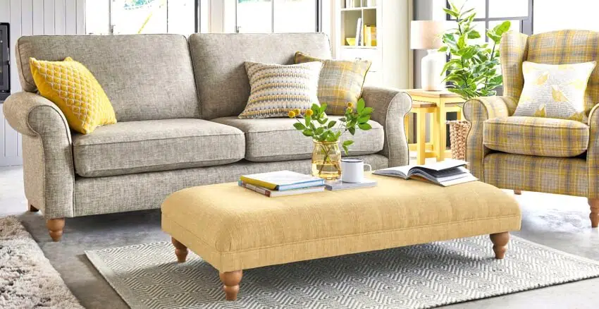 Beautiful living room with sofa, armchair, and yellow coffee table with books and flower in a vase