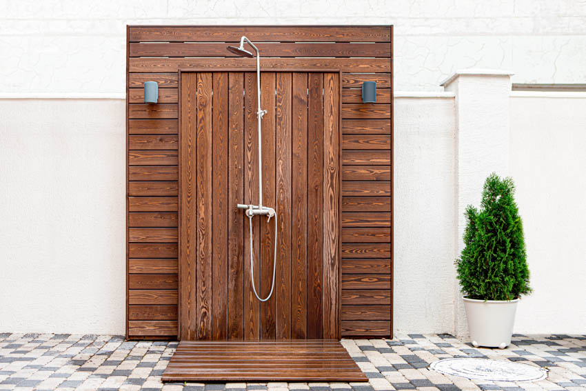 Shower with brown wooden panel walls with handheld shower