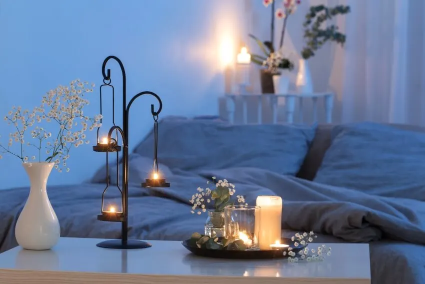 Bedroom with romantic candle lighting, antique candlestick, and flowers in vase