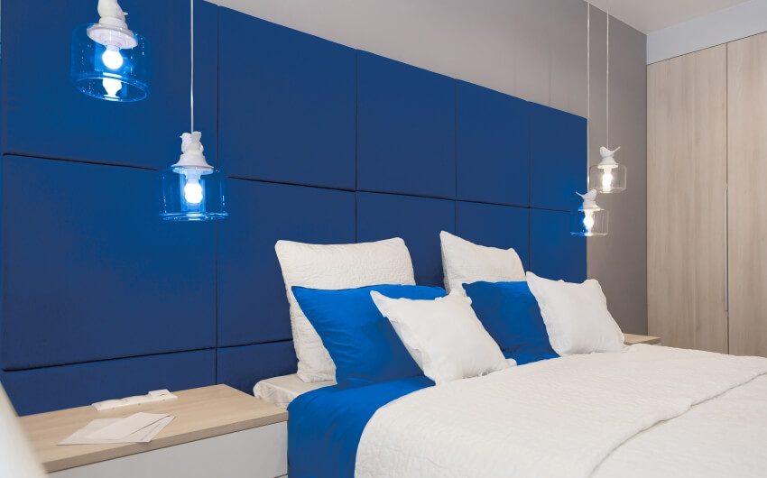 Bedroom with cozy bed, and blue mood light hanging over bedside table