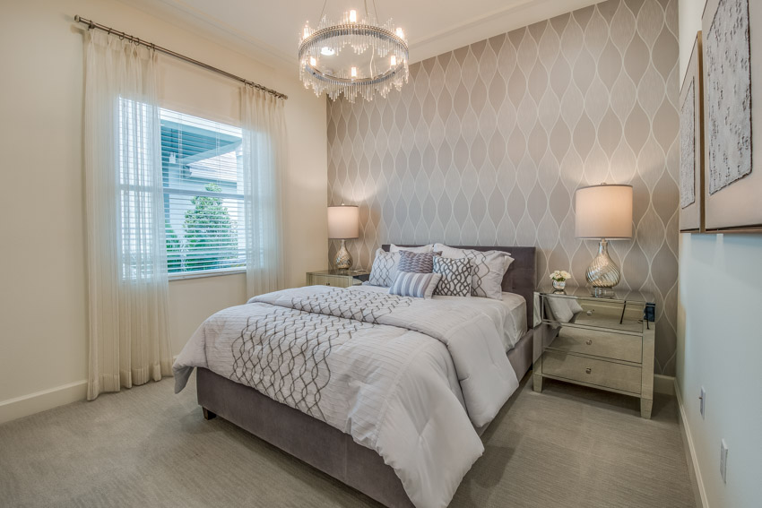 Bedroom with window, wallpaper, hanging light, nightstand, lamp, and bedsheets