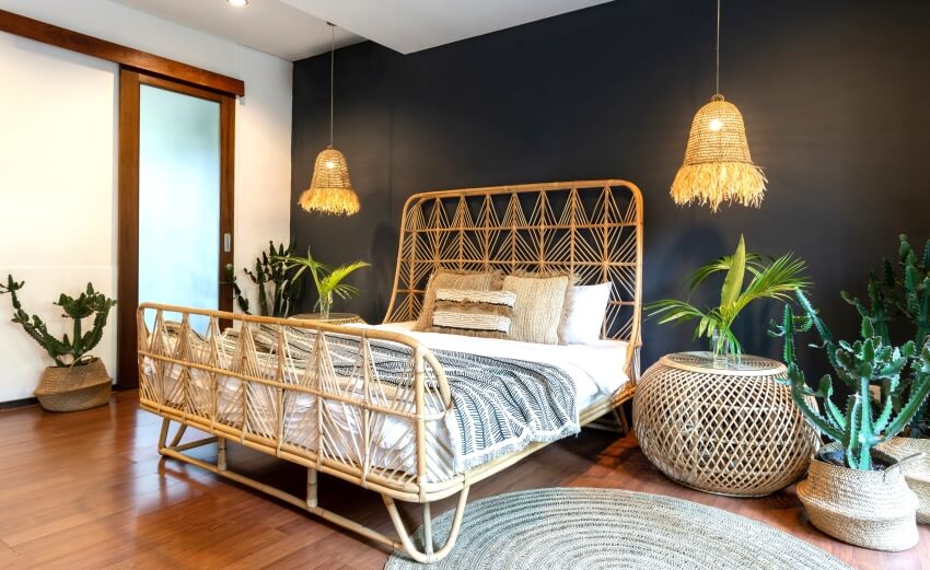 Bedroom with yellow light lamps over bedside tables, and wicker headrest at comfortable bamboo bed