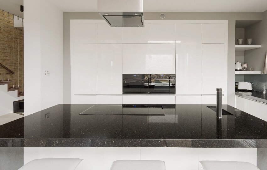 Black and white kitchen with laminate cabinets, and island with cooktop and granite countertop