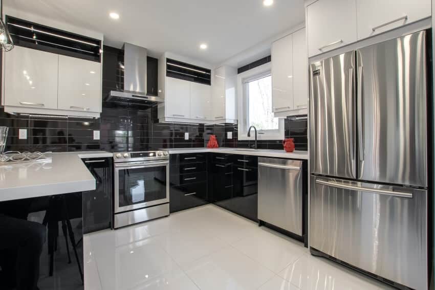 Black and white kitchen with stainless steel appliances, glossy cabinets, and tile backsplash