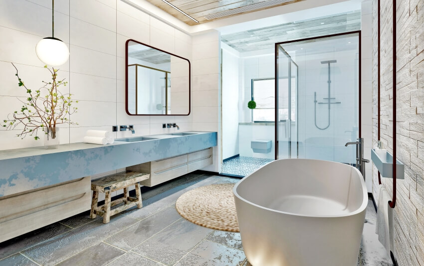 Bright bathroom with freestanding bathtub, pendant lights, brick wall, and a long vanity