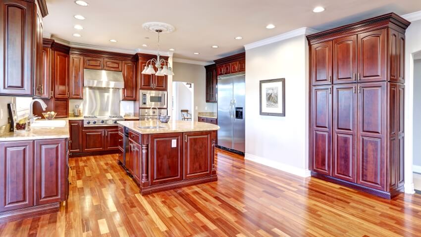 Bright kitchen with large kitchen island, cherry wood cabinets, sandy countertops, and panel floor
