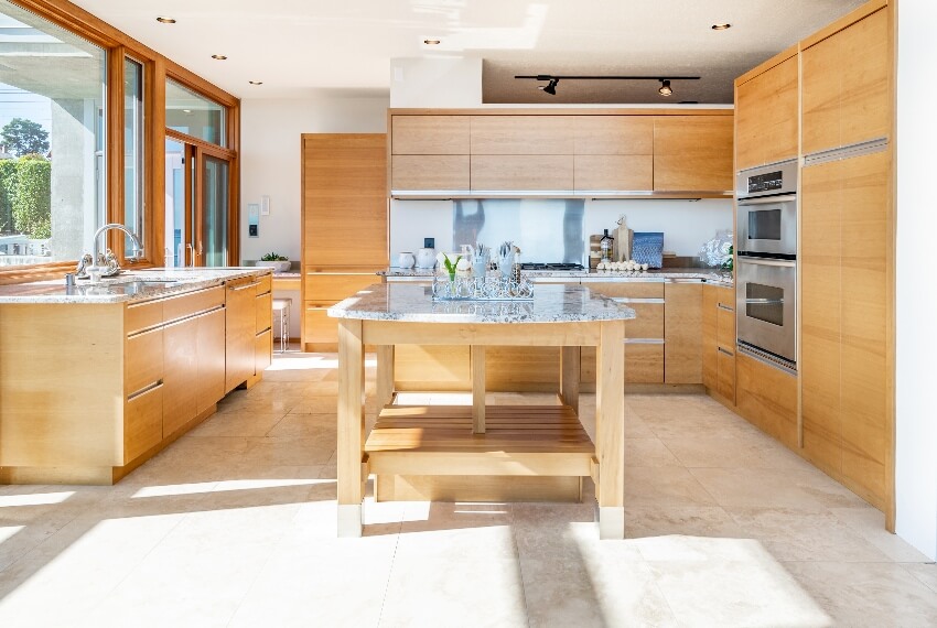 Bright kitchen with wood island, laminate cabinets, large windows, and marble tile floor