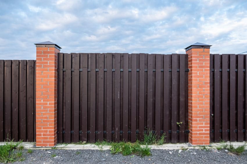 Brown composite fencing with brick pillars