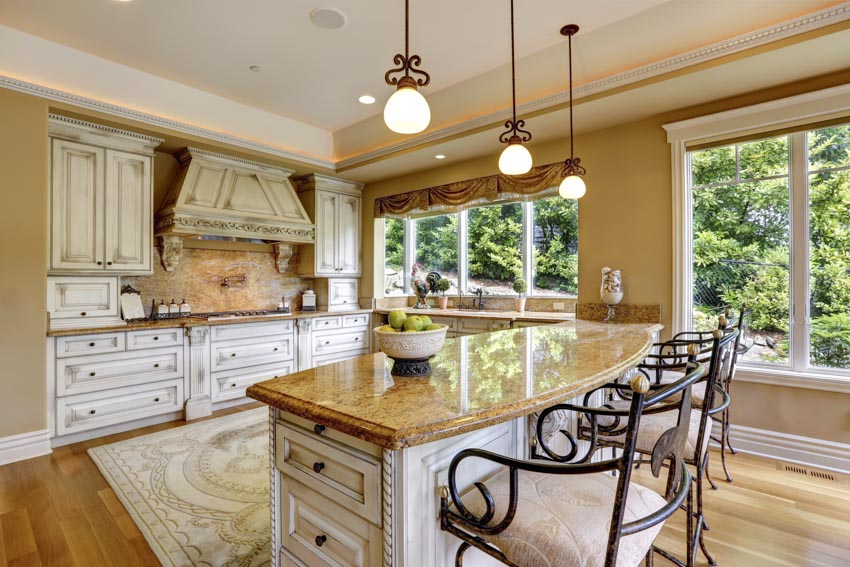 Classic kitchen design with granite backsplash, center island, countertop, pendant lights, and white cabinets