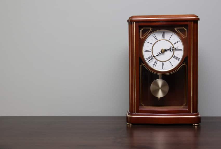 Clock with pendulum on top of wooden table