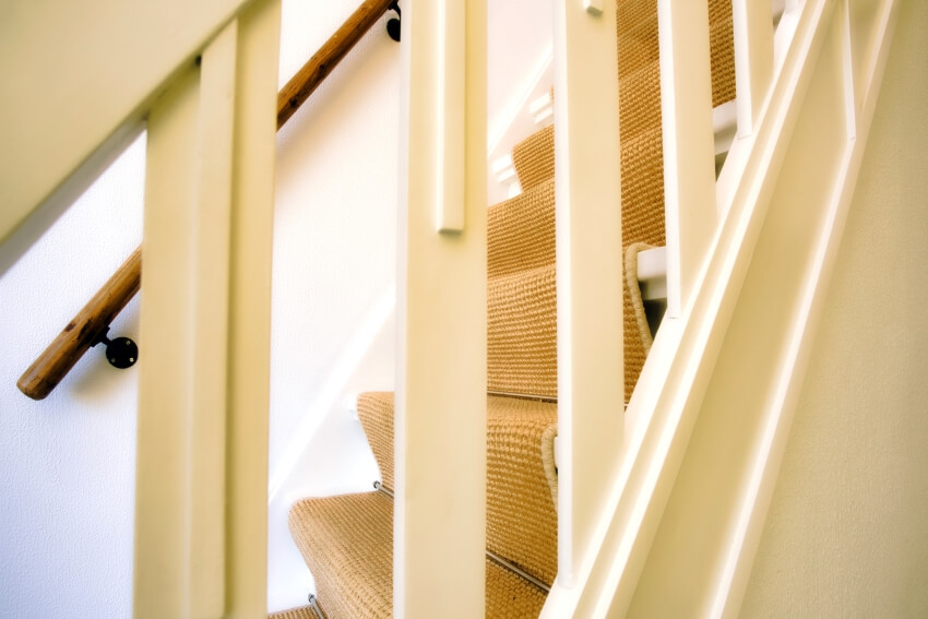 Close-up of a modern american design white wooden stairs with polypropylene carpet runner