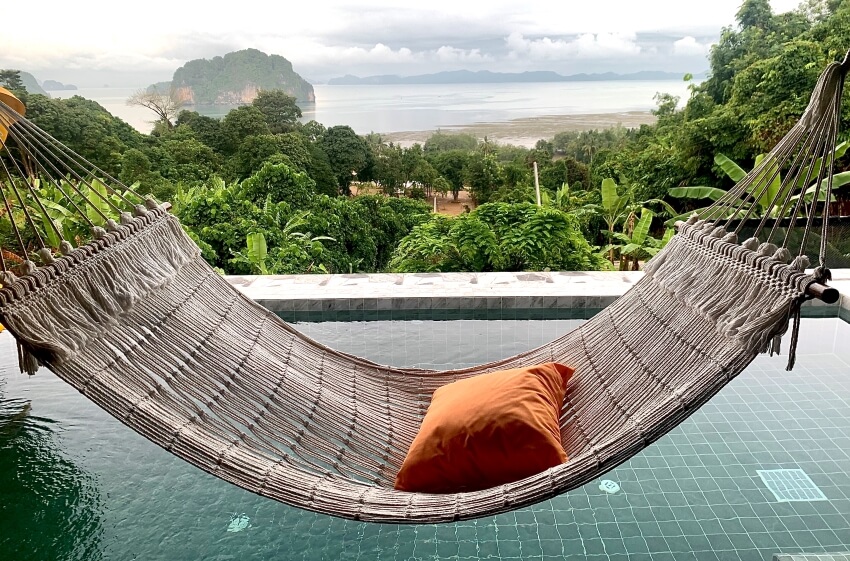Comfortable hammock with an orange pillow in te poolside of a luxury villa with beautiful seascape