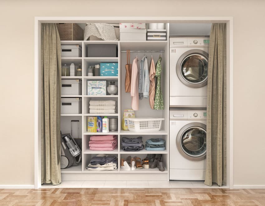 Compact laundry room with stackable washer dryer, open cabinets, and wood floor