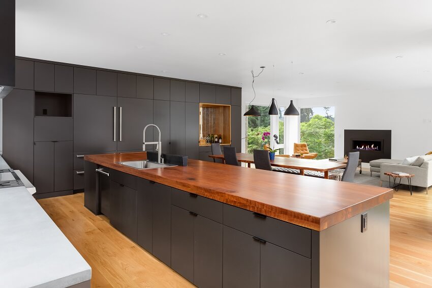Contemporary kitchen design with redwood island countertop, black cabinets, and wooden floors