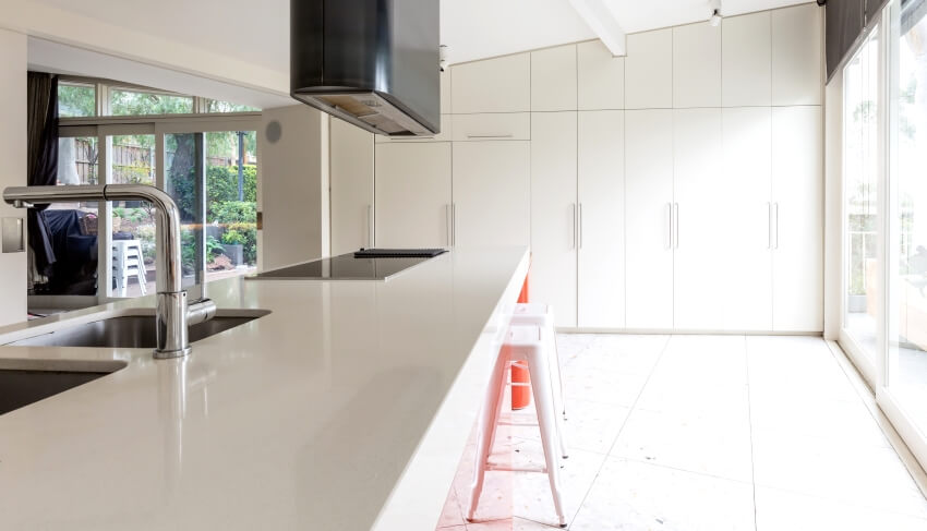 Contemporary white kitchen with island with stools cooktop and sink, and terrazzo floor