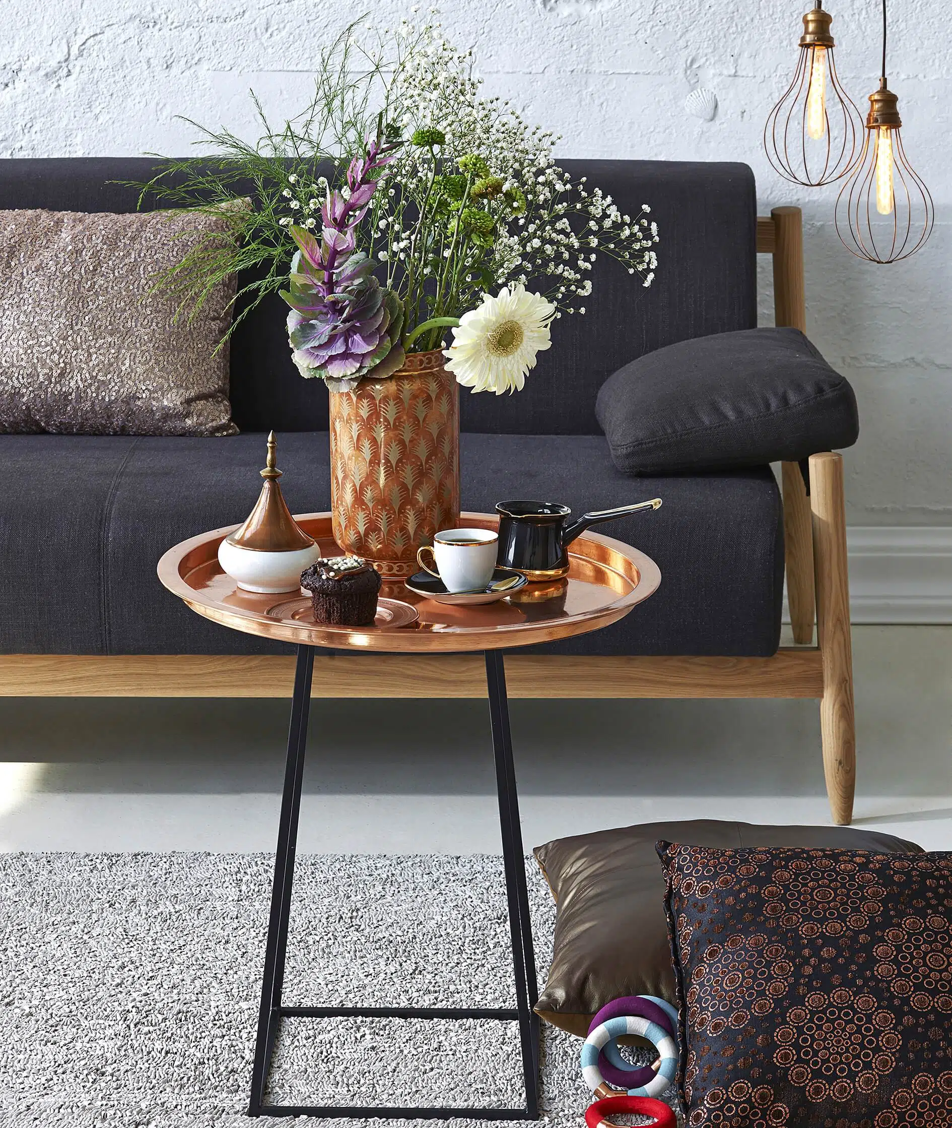 Copper coffee table, sofa, modern lamp, and throw pillows on the carpet of a living room