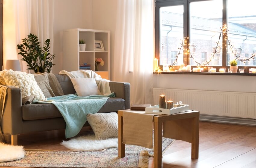 Cushioned sofa, coffee table, string lights and candles on window sill in a cozy living room